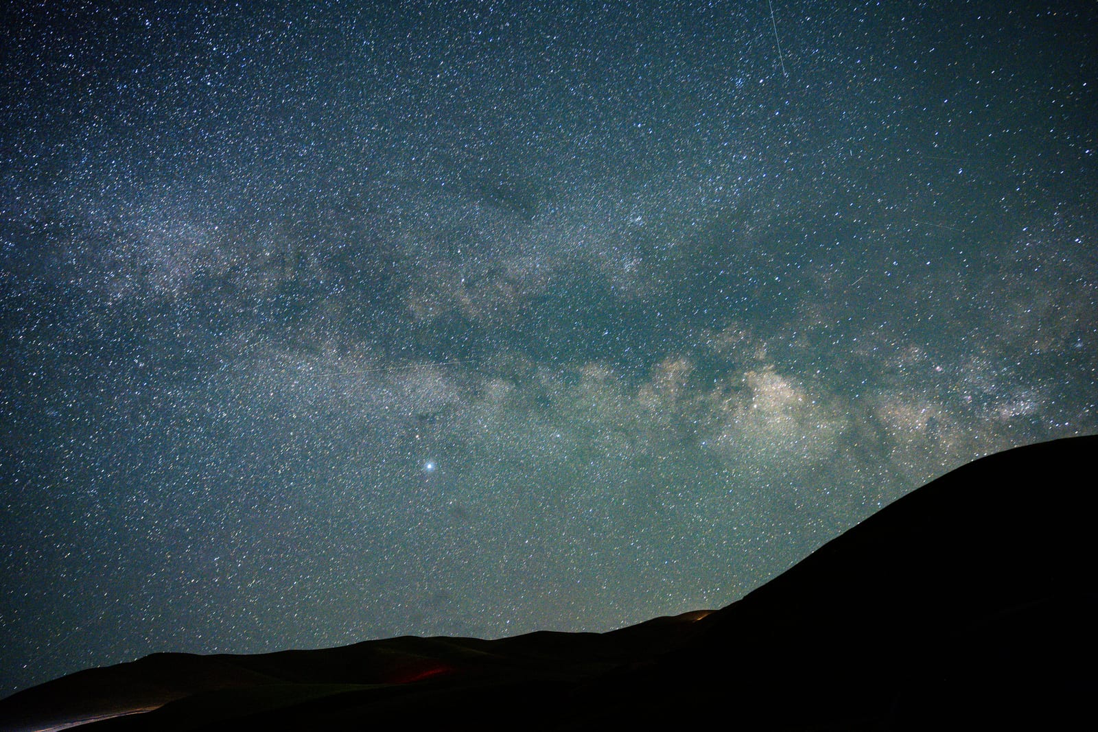 Milky Way band above a dark hillside silhouette