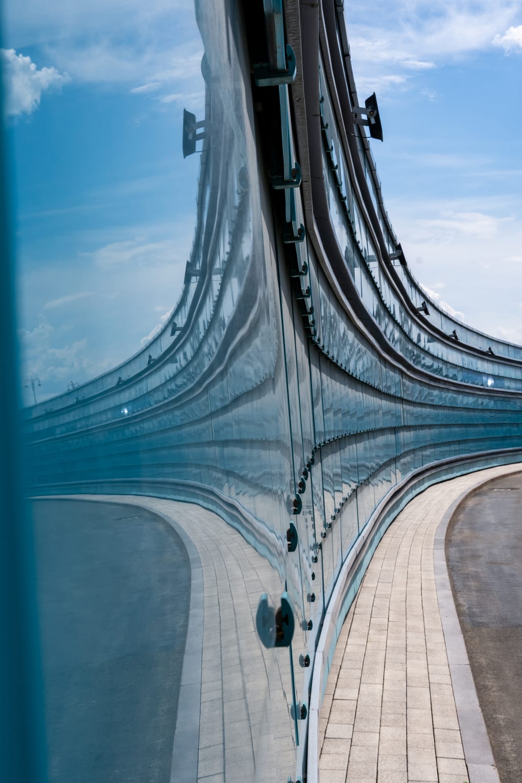 Abstract curving blue glass facade reflecting sky