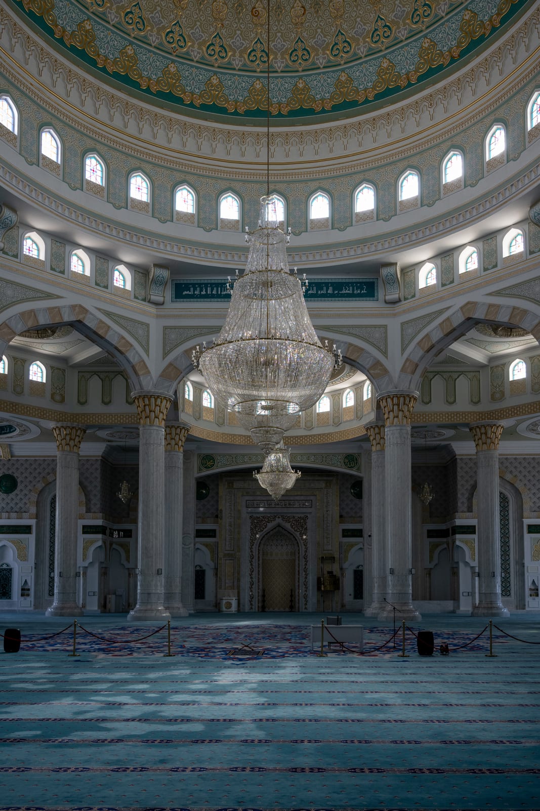 Mosque interior with domed ceiling, chandelier and patterned blue carpet