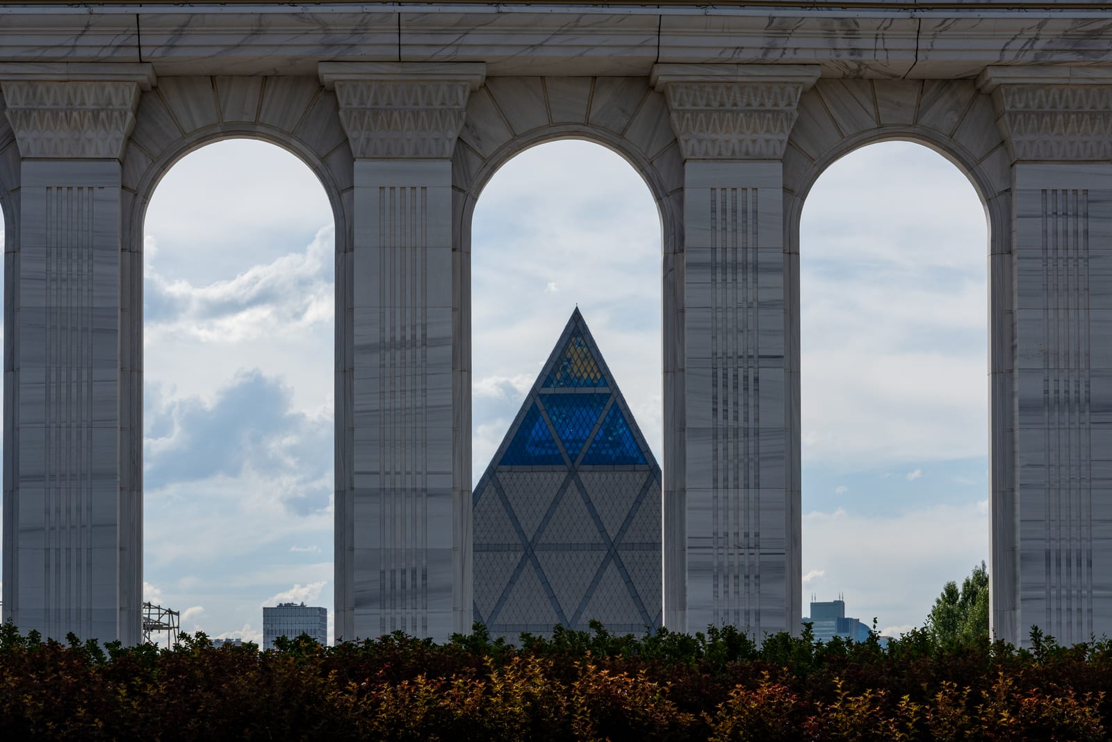 Glass pyramid framed through a row of stone arches