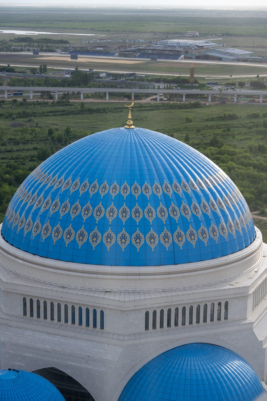 Patterned blue mosque dome seen from above with the plain beyond
