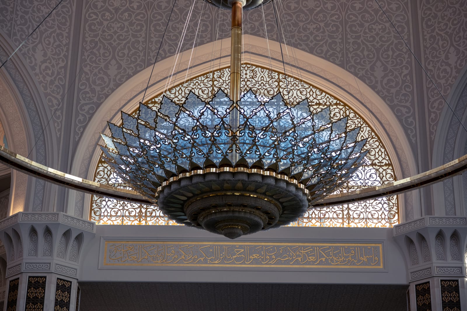 Large crystal chandelier hanging under a ring in the mosque hall