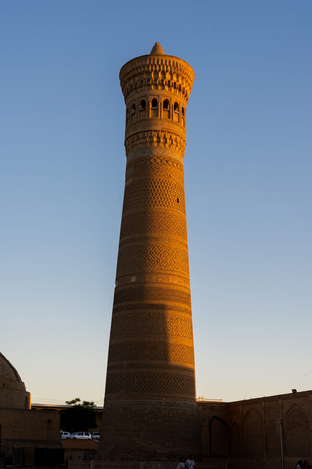 Kalyan minaret glowing orange in low sun against a dusky sky