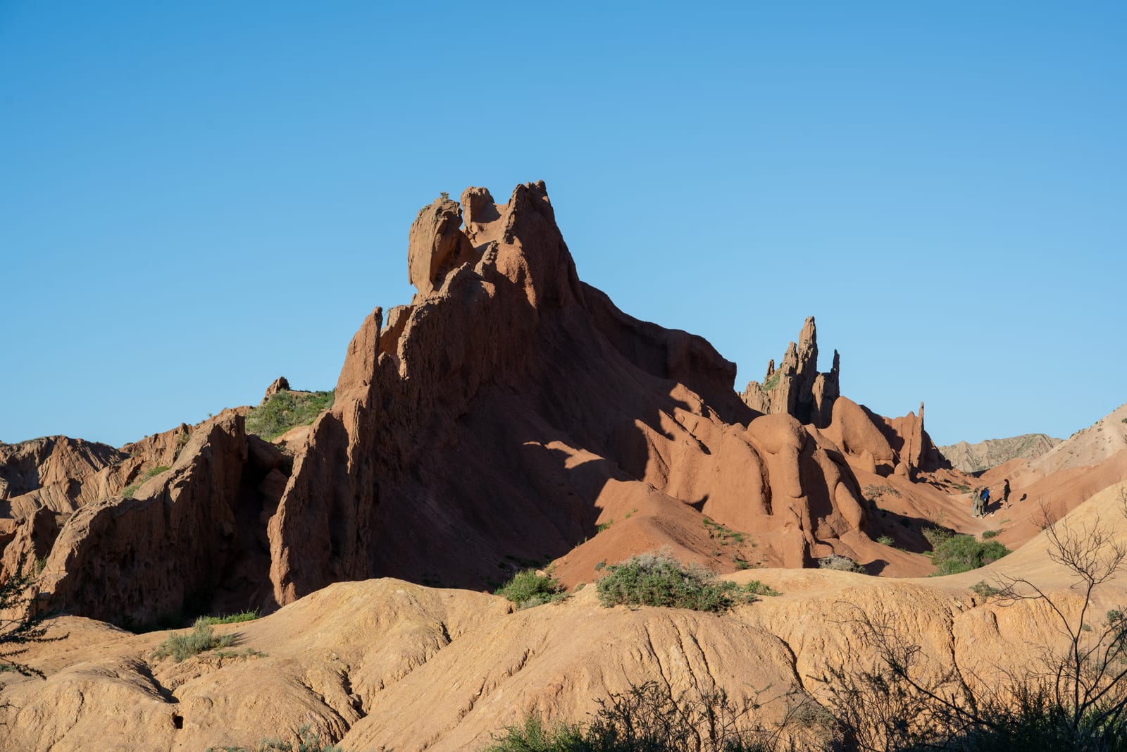 Jagged red sandstone ridge rising from pale badlands under clear blue sky