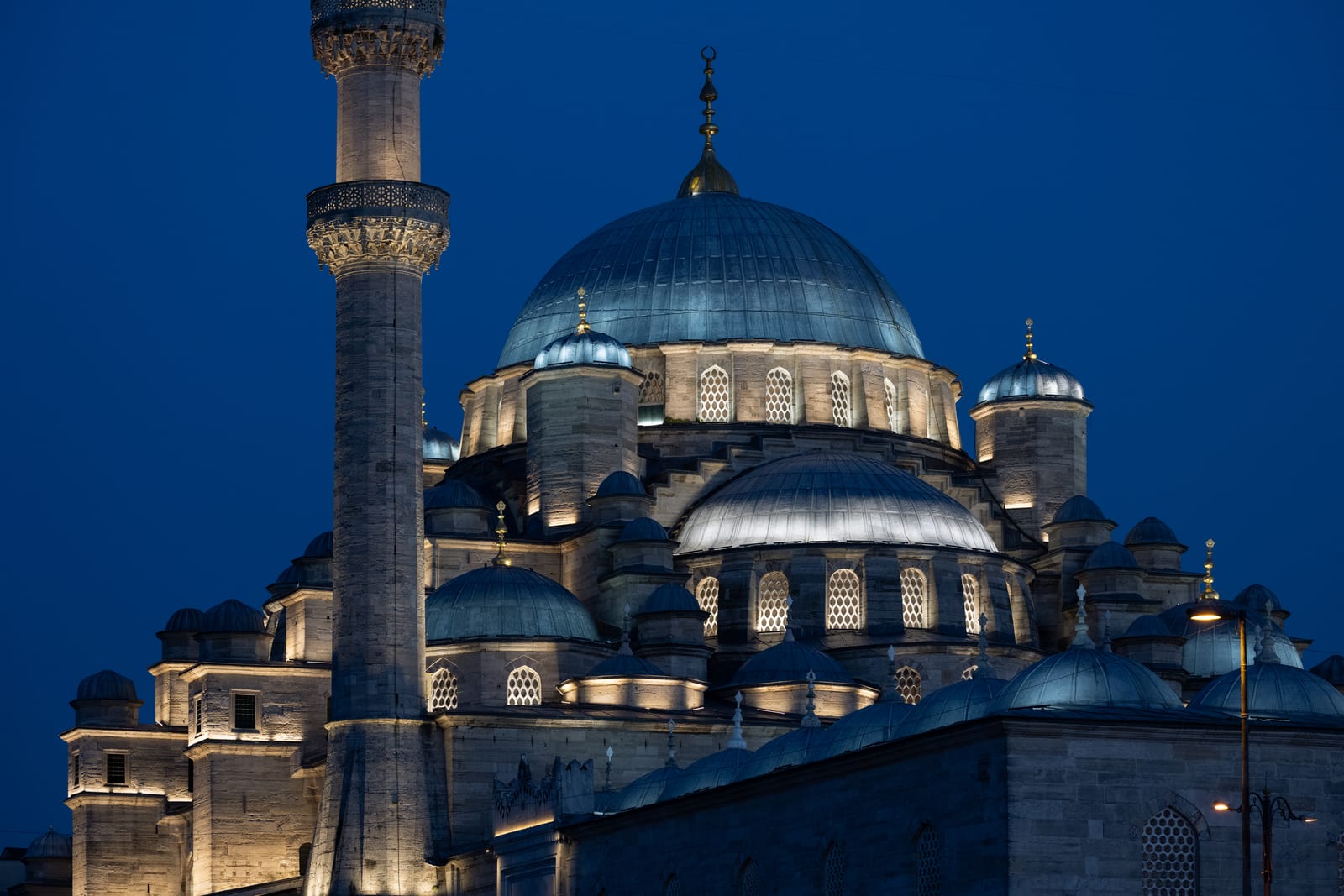 Floodlit New Mosque domes and minaret against a deep blue-hour sky