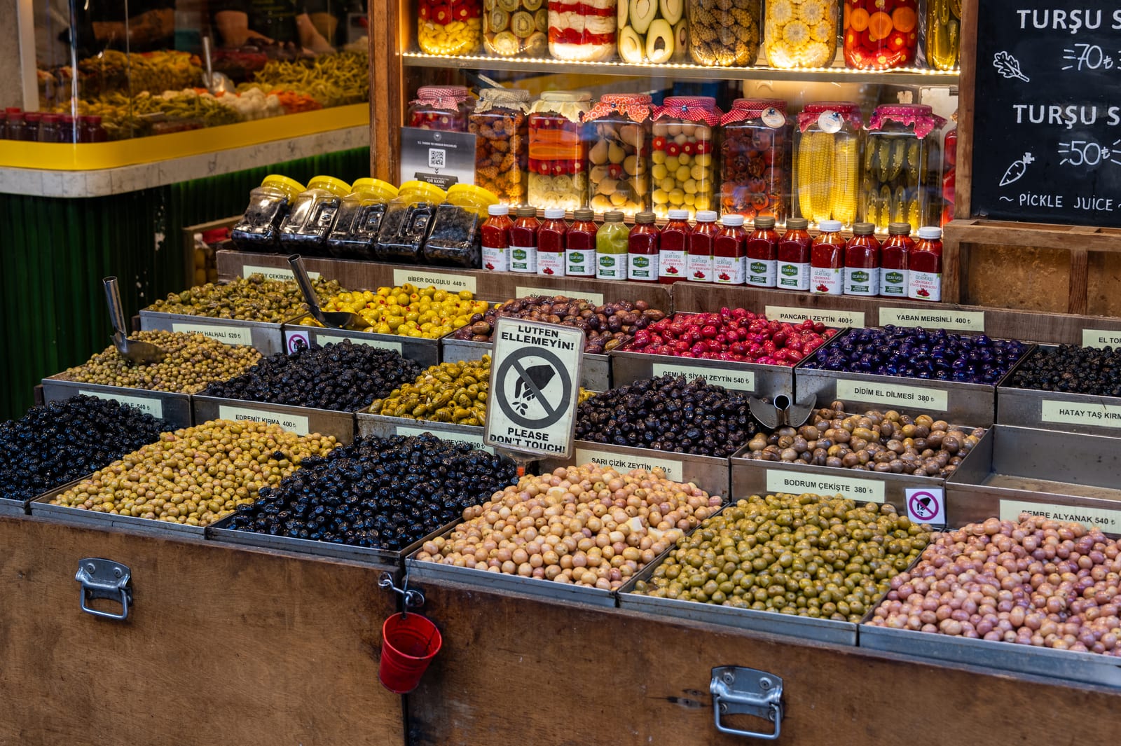 Colourful market stall of olives and pickle jars under warm lights