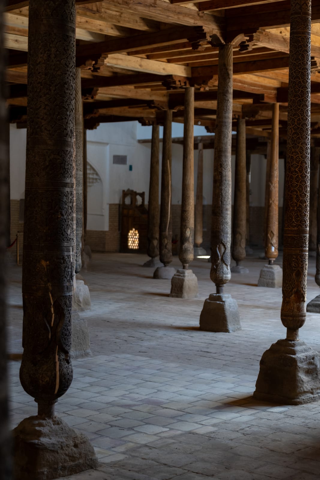 Forest of carved wooden columns in the Juma Mosque with shafts of light on the floor