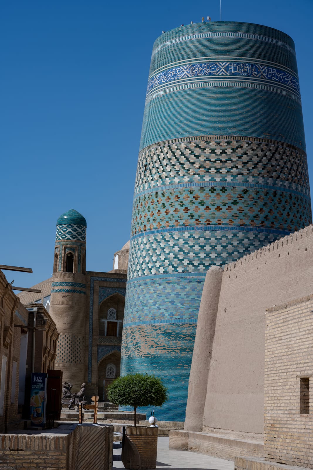 Squat turquoise-banded Kalta Minor minaret rising above the old-town street