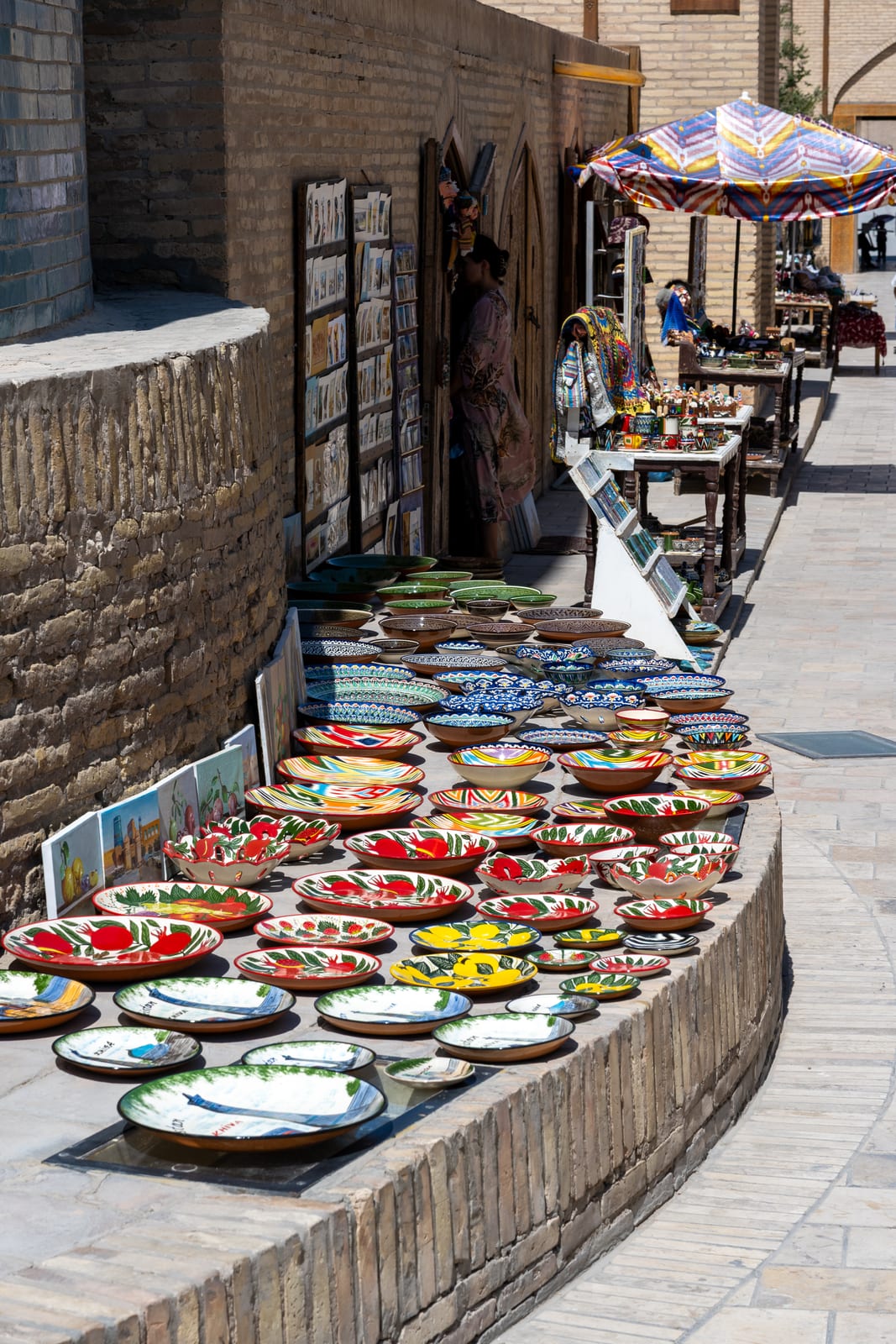 Curving display of brightly painted ceramic plates along a brick wall