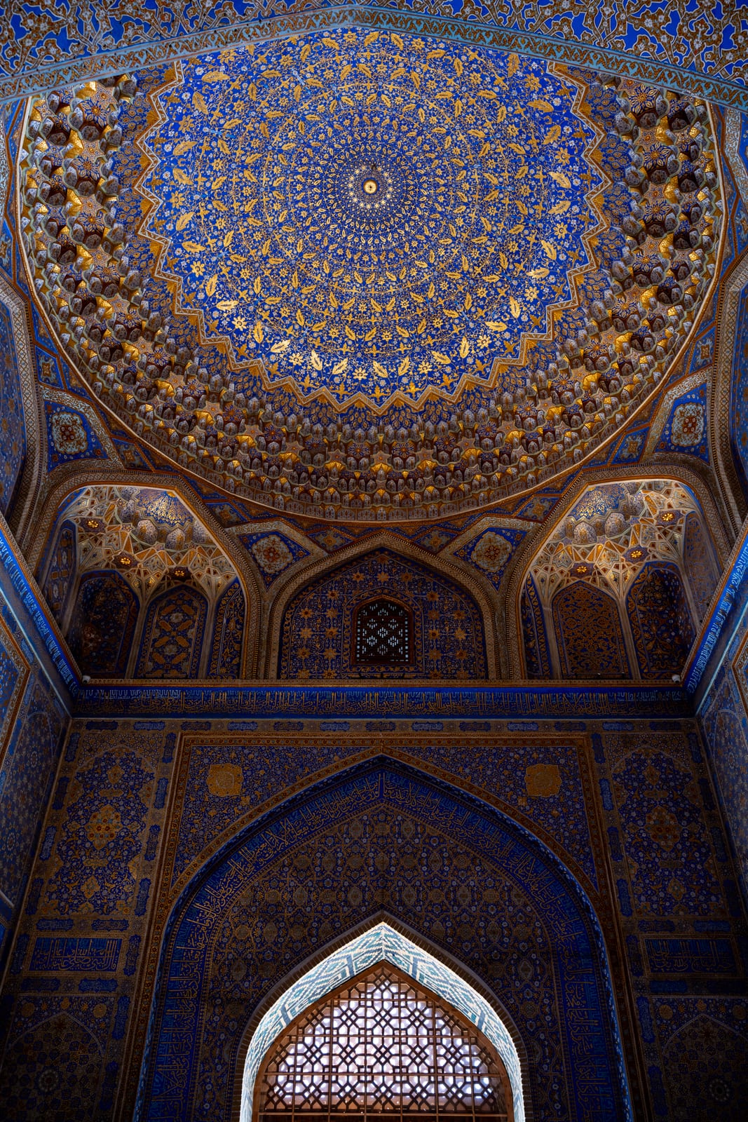 Gilded blue dome interior of a madrasa mosque with a latticed window below