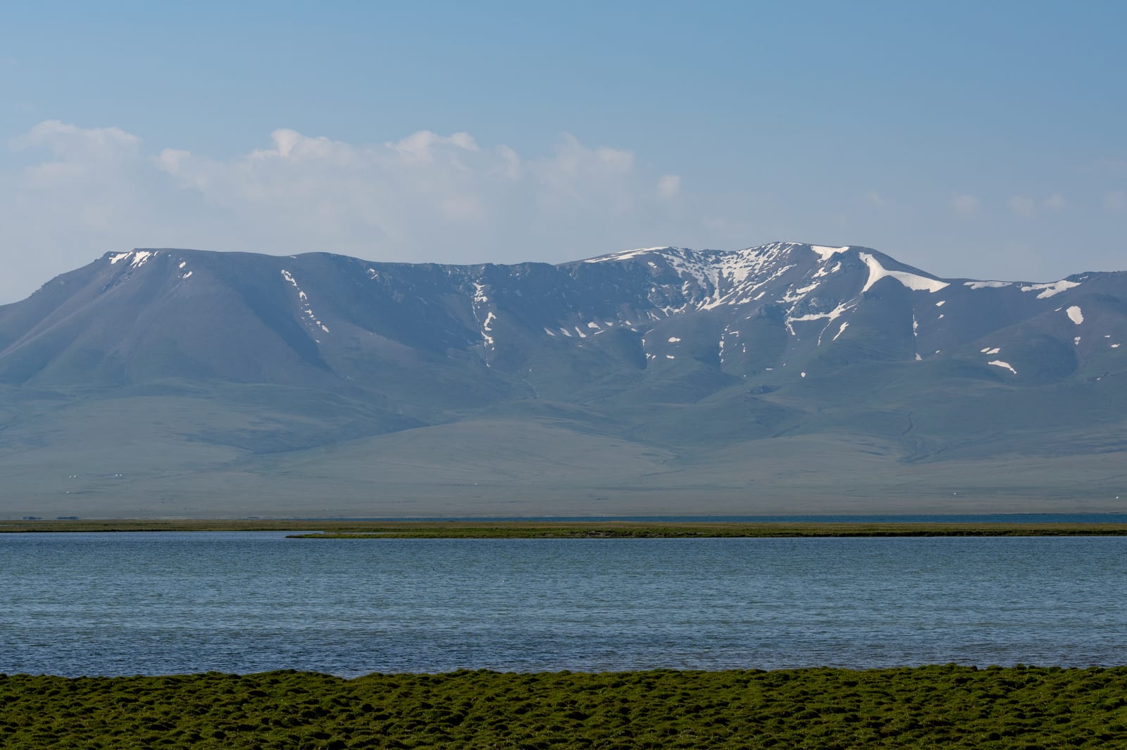 Minimal bands of green shore, blue lake and snow-streaked mountains