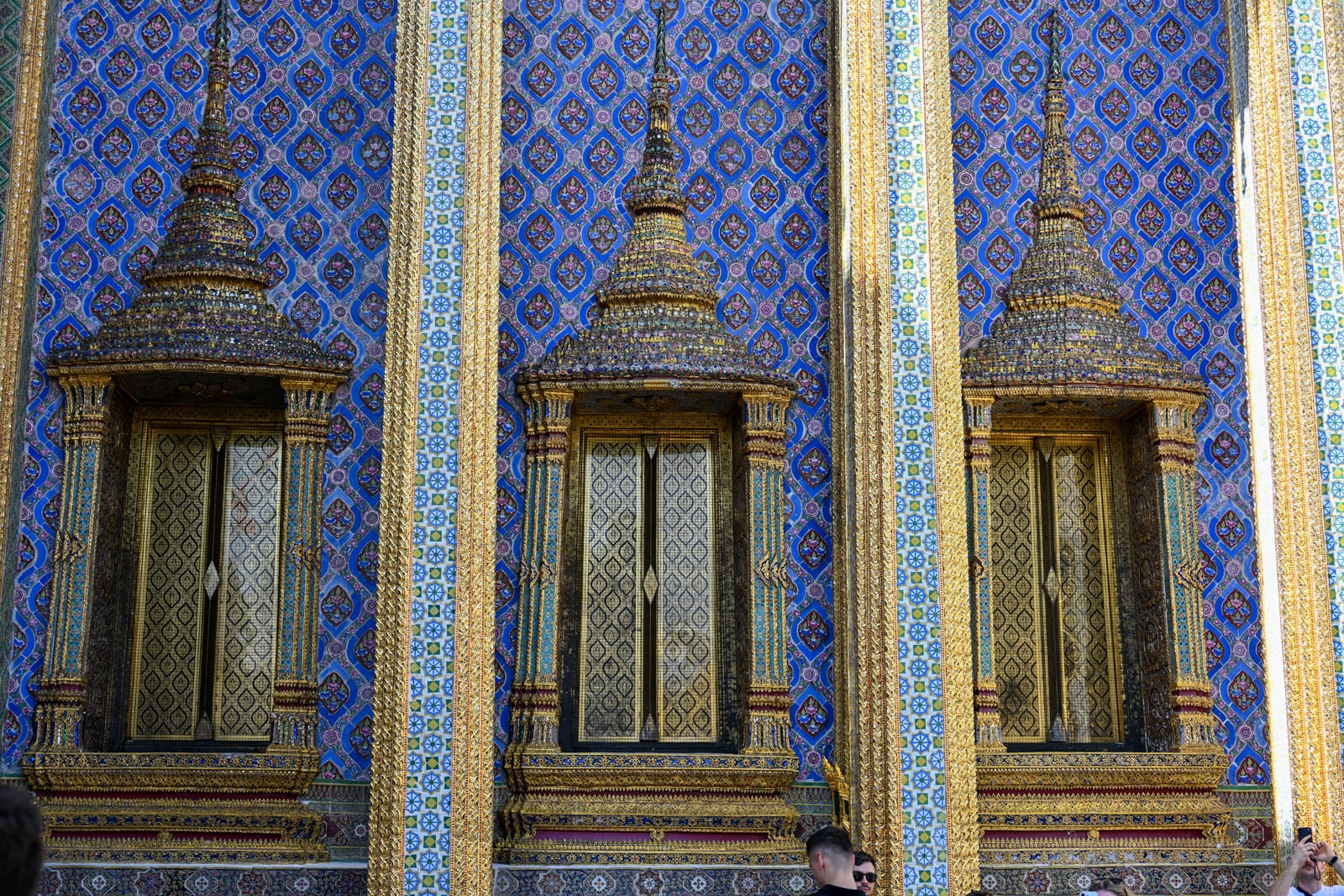 Three gilded spired windows set in blue patterned tile wall