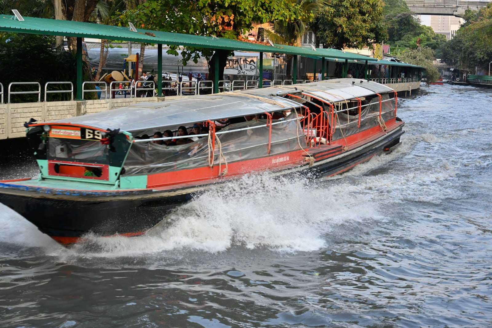 Canal passenger boat throwing spray as it passes a pier