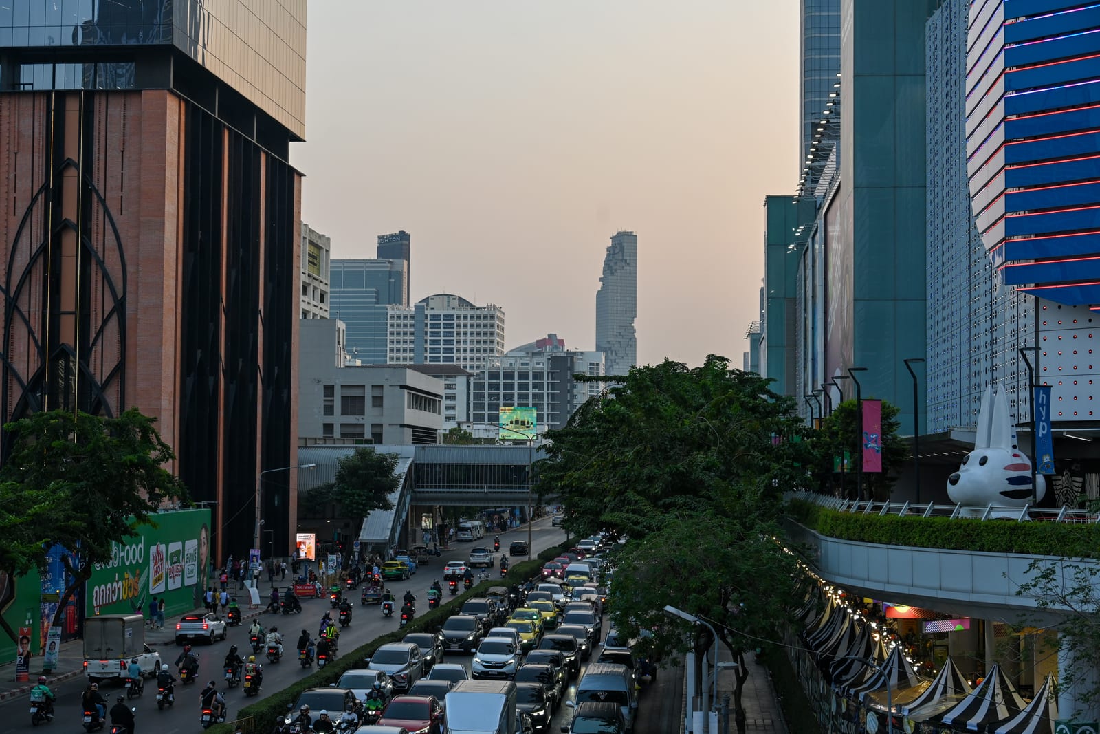 Traffic-filled avenue between towers at hazy dusk