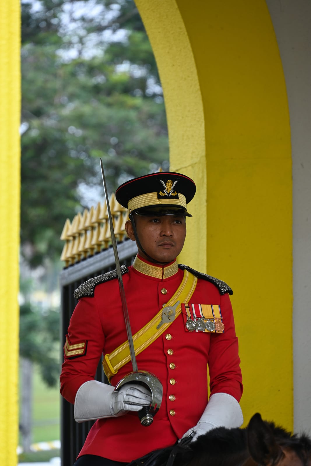 Royal guard in red dress uniform with sword framed by a yellow arch