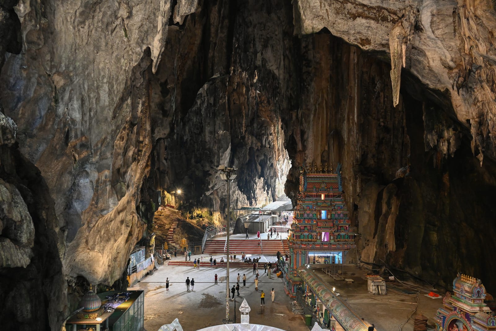 Vast Batu Caves interior with stalactites and small temple on the cave floor