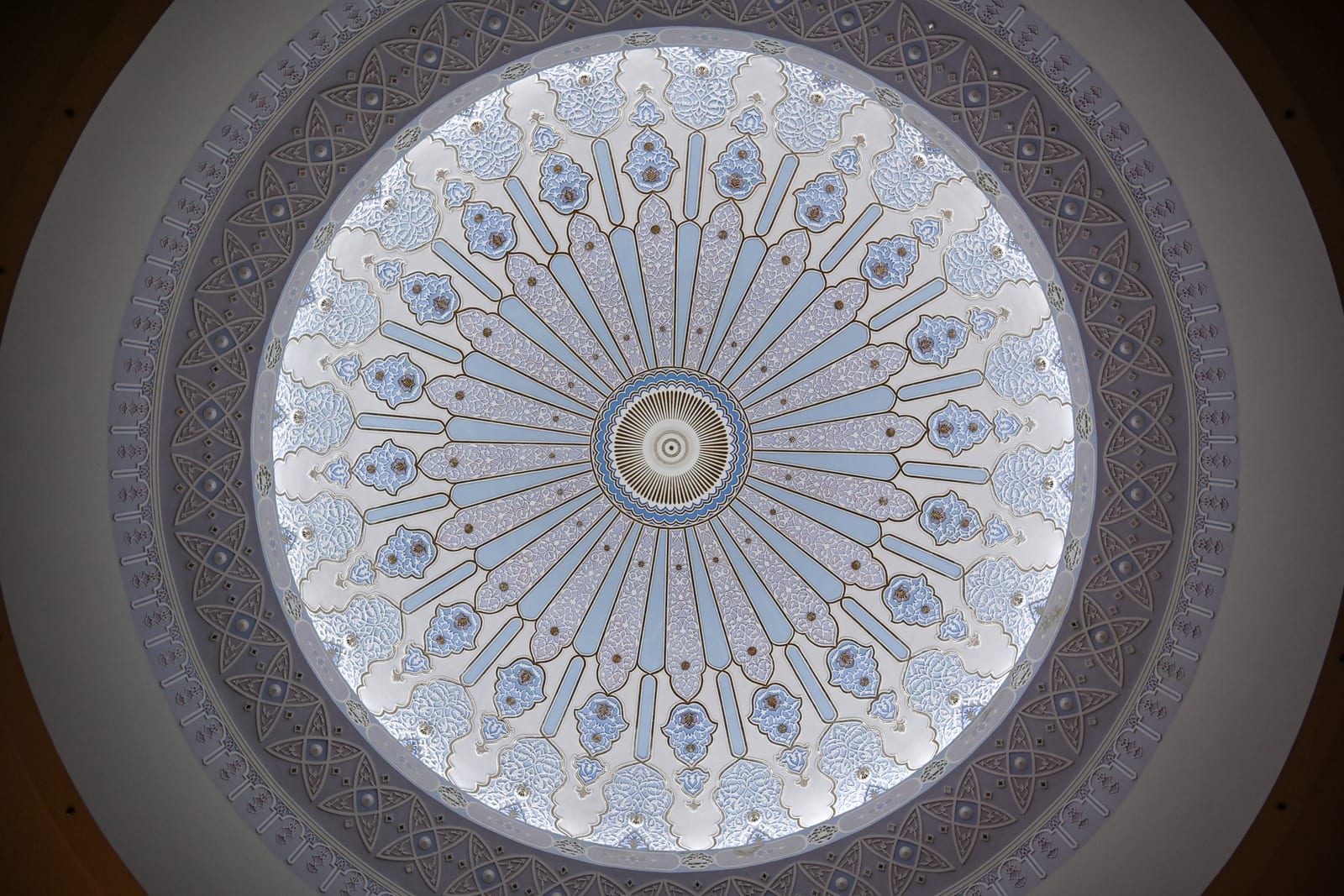 Symmetrical view up into a patterned blue and white mosque dome