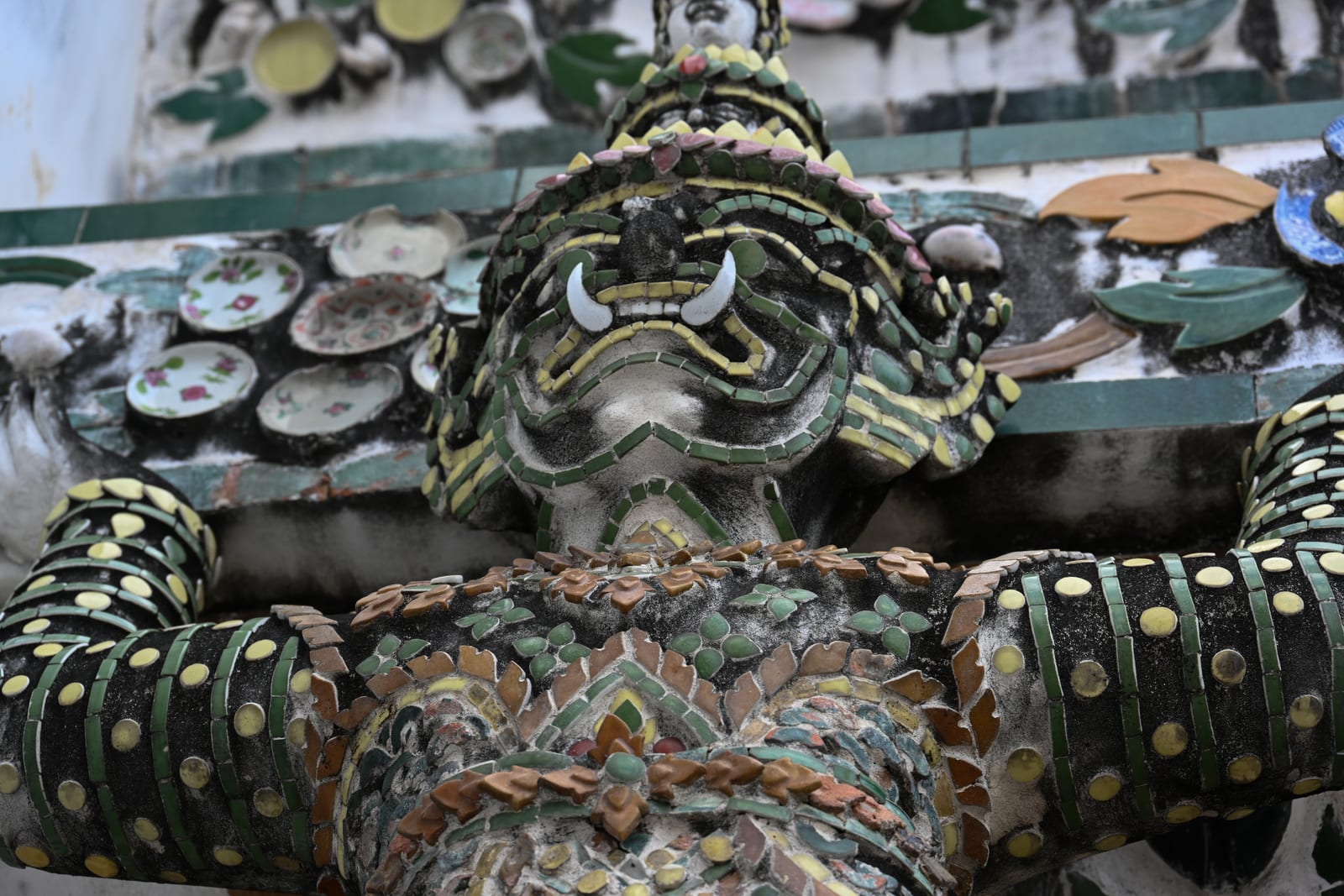 Close-up of a porcelain-mosaic demon figure supporting Wat Arun