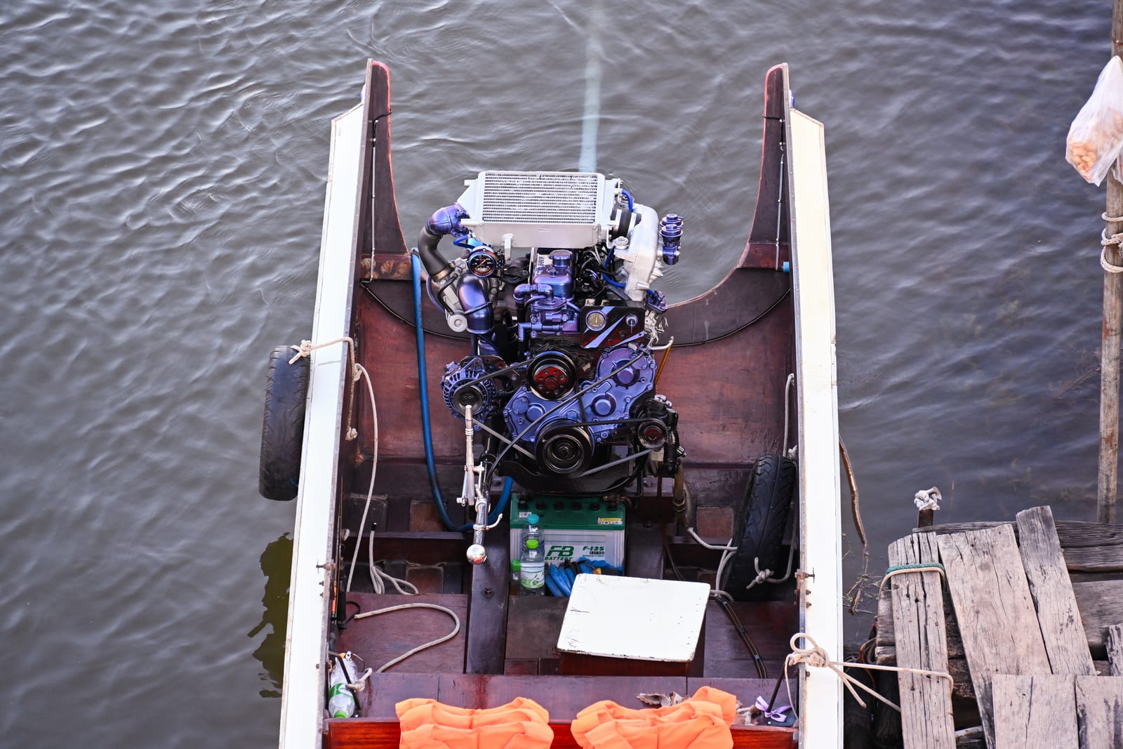 Top-down view of a longtail boat stern with exposed engine on rippled water