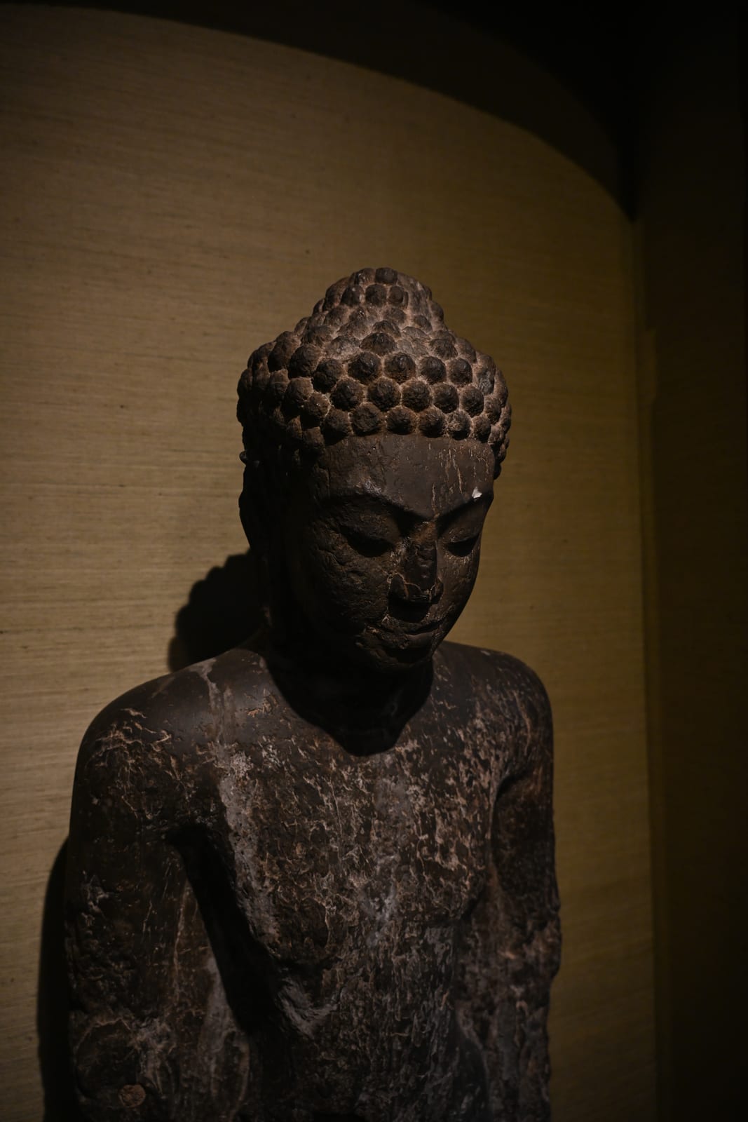 Stone Buddha torso in a niche under moody side light
