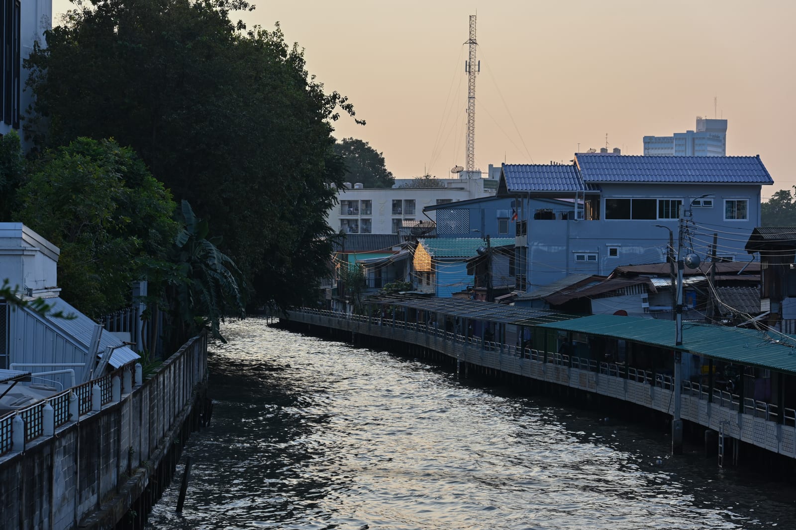 Bangkok canal at dusk with blue houses and pink sky